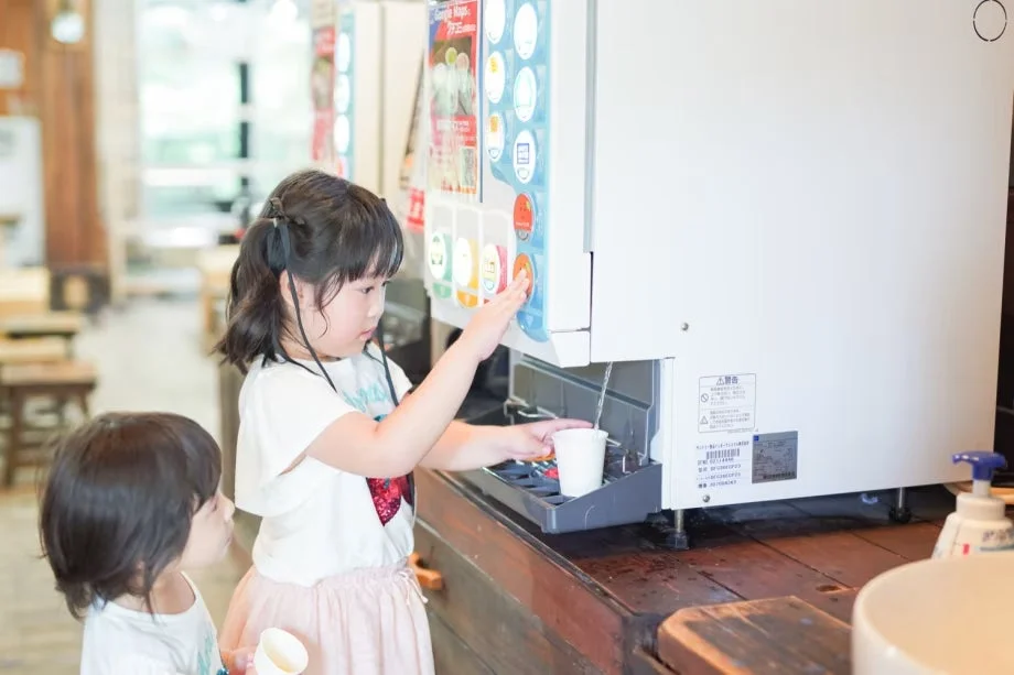 ドリンクバーで飲み物を注ぐ子供
