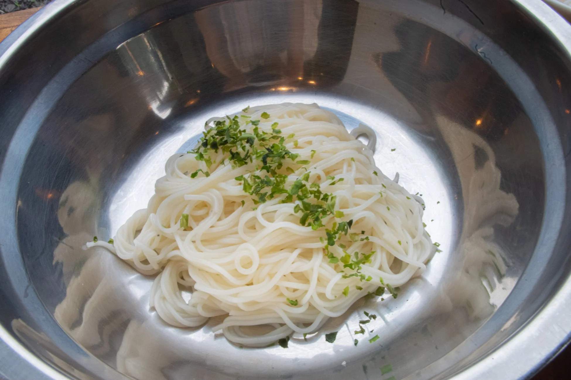 銀色のボウルに盛られた白い細麺にハーブがトッピング
