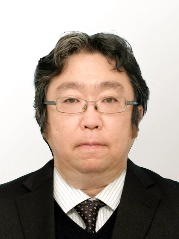黒いスーツとストライプのシャツにネクタイを着用し、メガネをかけた中年の男性