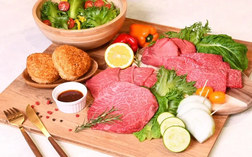 木製ボードに盛り付けられた霜降り牛肉、焼おにぎり、色鮮やかな野菜サラダ、レモンなどが並ぶ豪華な食材セット。