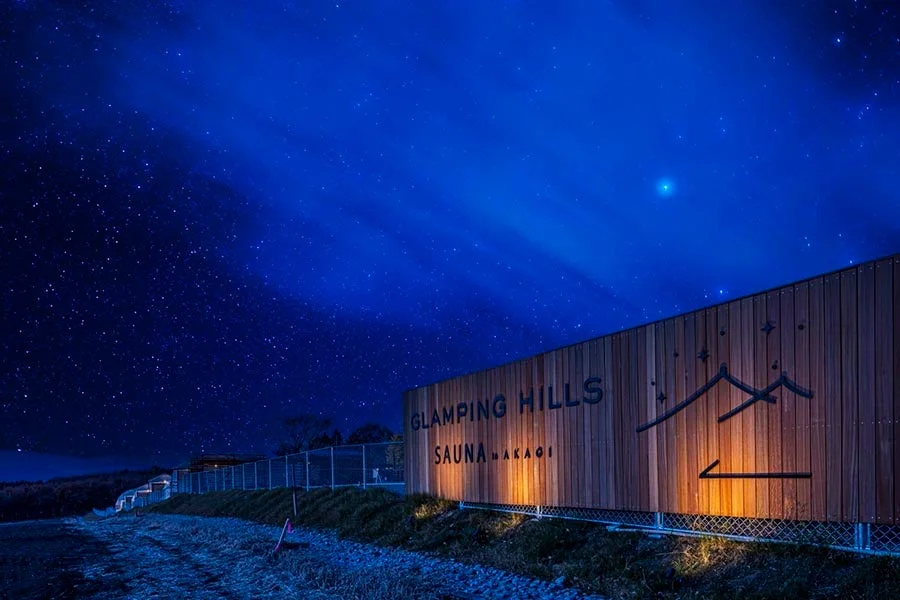 満天の星が輝く夜空の下、「GLAMPING HILLS SAUNA MAKAGI」の施設がライトアップされています