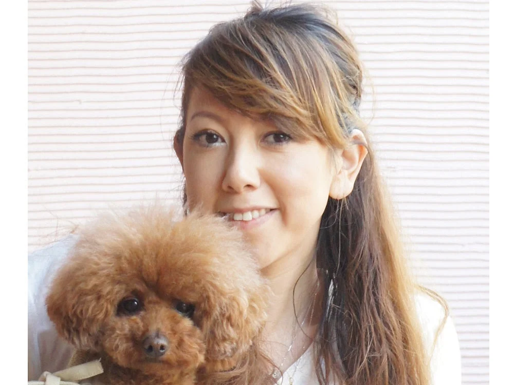 トイプードルを抱っこして笑顔の女性