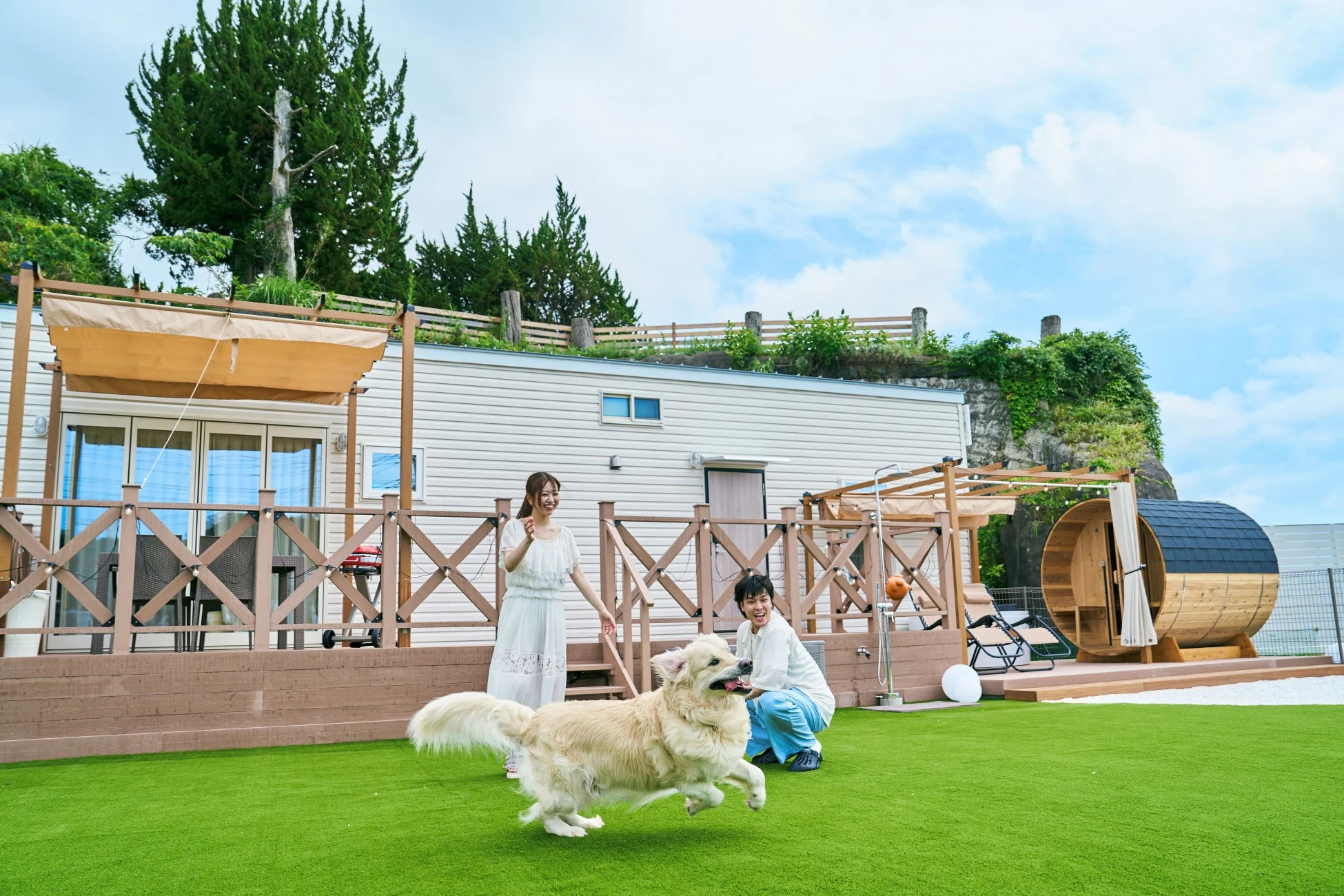カップルと愛犬がドッグランで遊ぶ様子