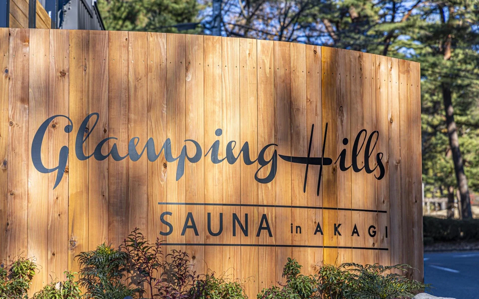 木製の看板に「Glamping Hills SAUNA in AKAGI」と書かれた施設のエントランスサイン