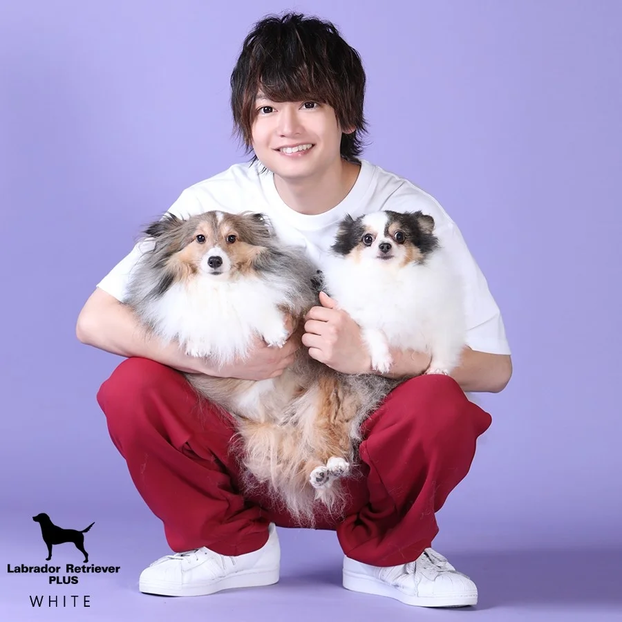 紫の背景で犬を抱く男性