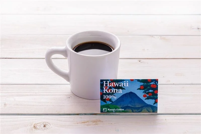 白いマグカップに入ったコーヒーとハワイコナ100%のパッケージ