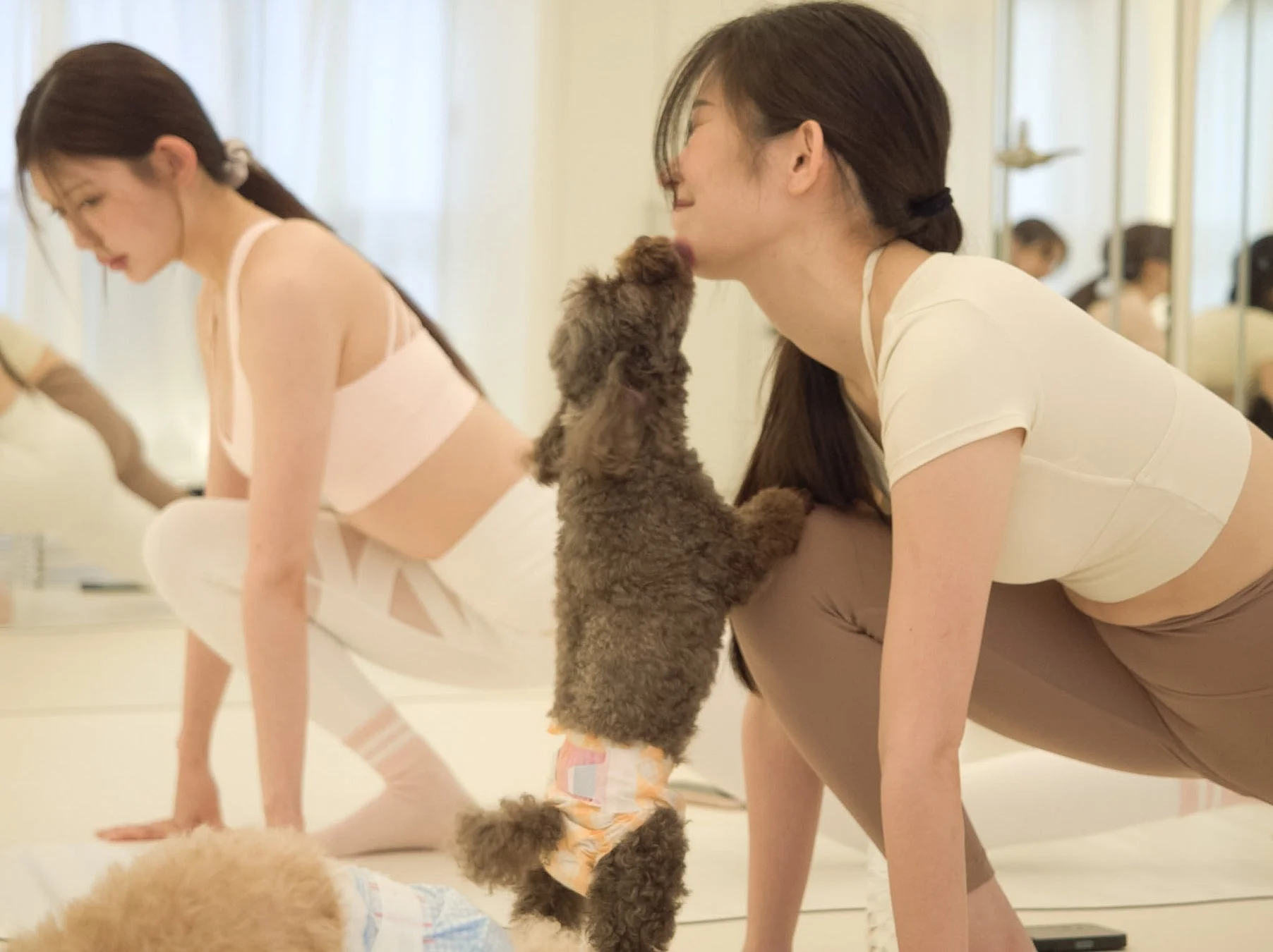 女性が犬に顔を舐められているヨガ風景