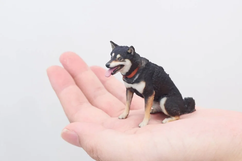 手のひらにちょこんと乗せられた黒柴のリアルなミニチュアフィギュア