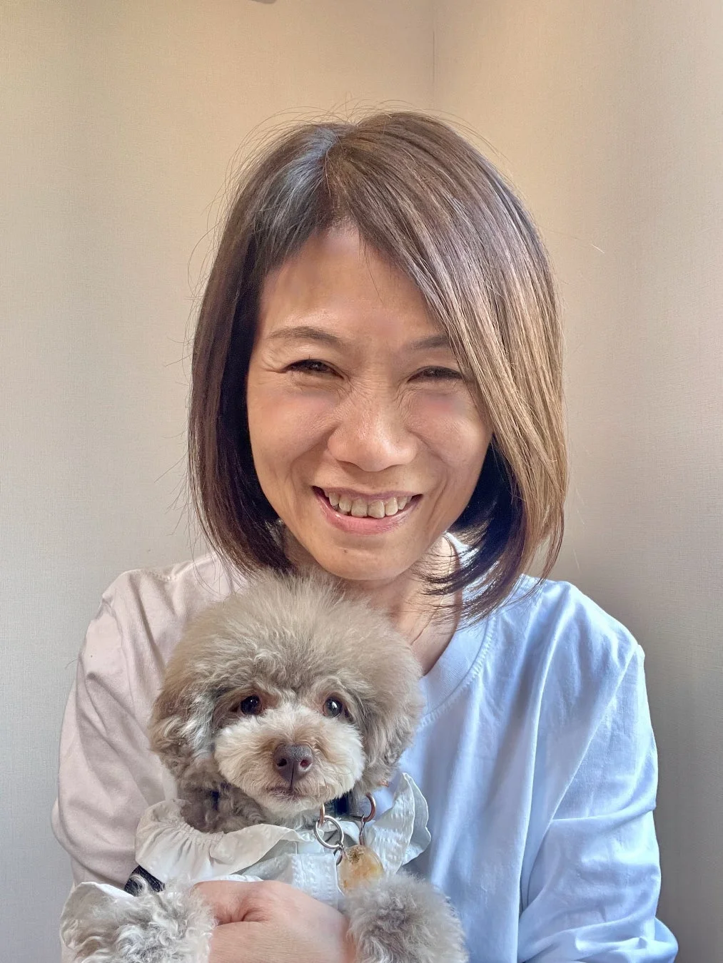 笑顔の女性が小さな可愛らしい犬を抱っこしているポートレート写真