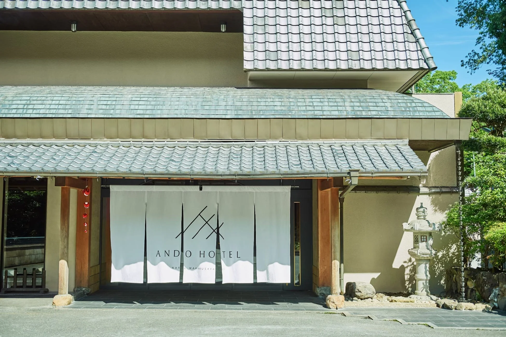 和風建築の入り口に白い暖簾がかかり、「ANDO HOTEL NARA WAKAKUSAYA」の文字が見えます
