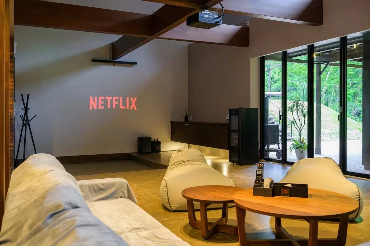 Netflixが映し出された壁と快適なソファが配置されたモダンなリビングルーム