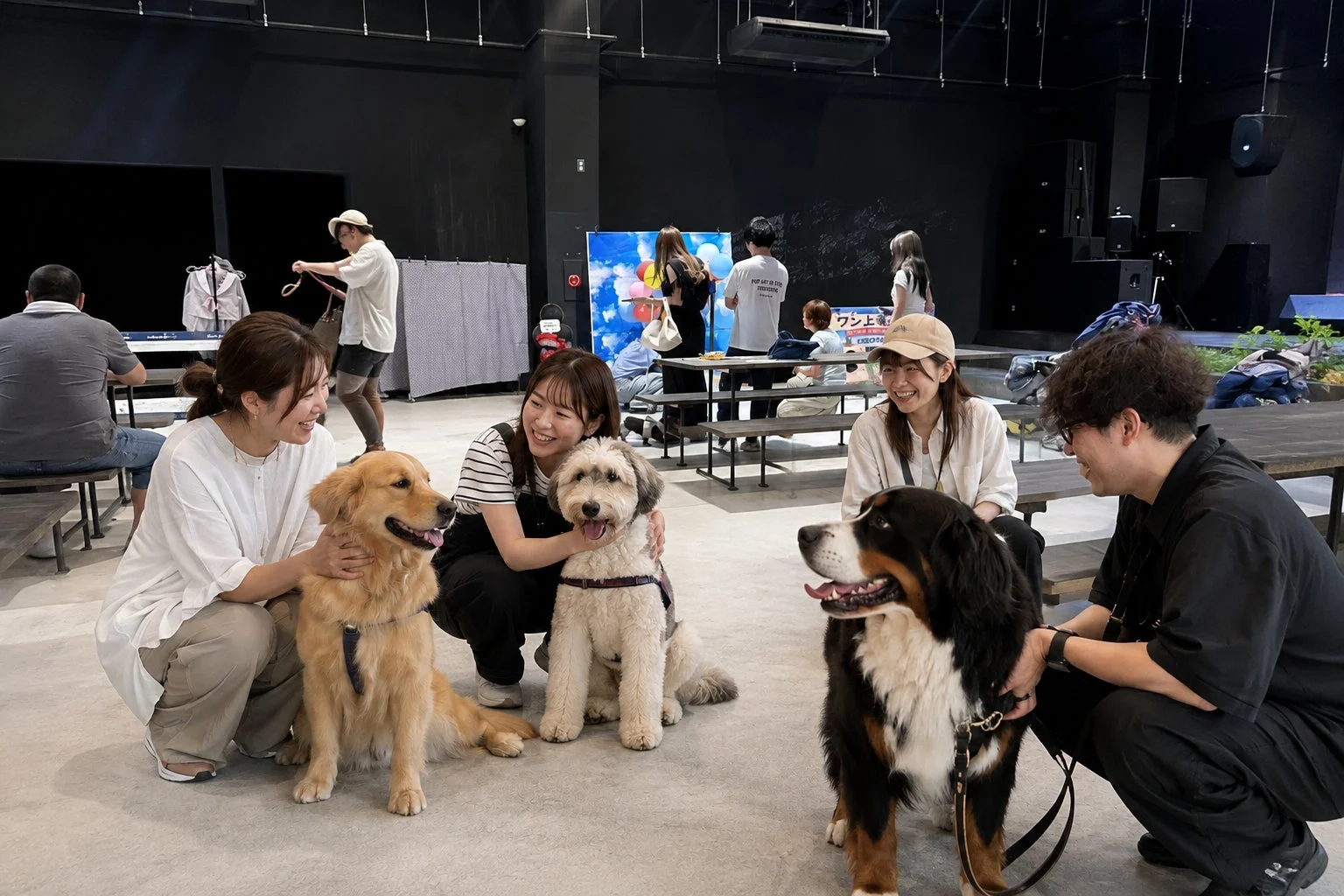 屋内イベントスペースで、人々が愛犬たちと楽しそうに交流している様子です。
