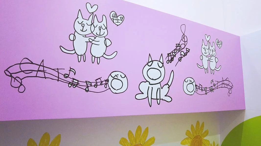 ピンクの壁に描かれた猫たちのイラスト