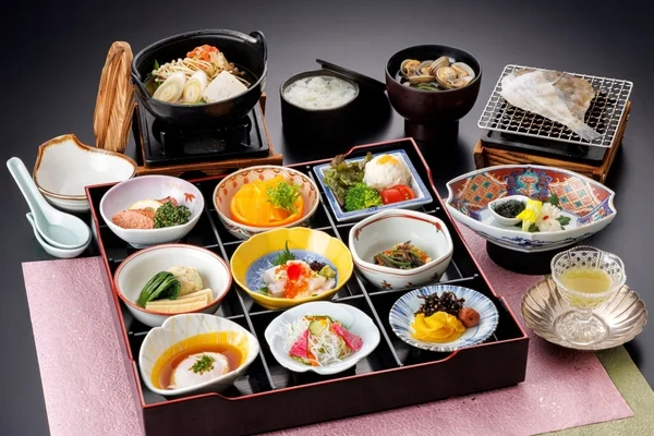 豪華な和食の御膳が黒い背景に美しく盛り付けられています